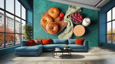 Wooden board with tasty bagels, berries and bottle of milk on green background Wall mural