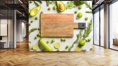 Wooden cutting board with green food on white background Wall mural