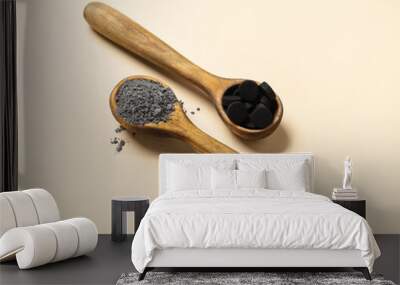 Wooden spoons with of activated carbon facial mask and pills on color background Wall mural