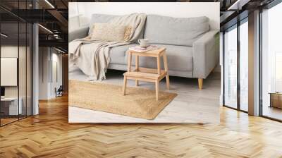 Wooden stepladder stool with cup, magazine and eyeglasses near sofa in living room Wall mural