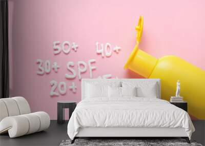 Word SPF and numbers made of cream with bottle of sunscreen on pink background Wall mural