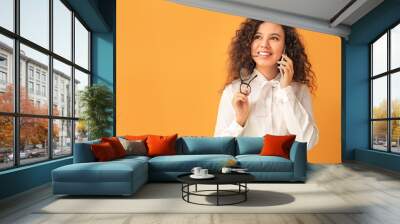 Young African-American businesswoman talking by phone on color background Wall mural