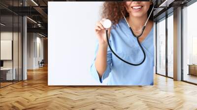 Young African-American nurse with stethoscope on light background Wall mural