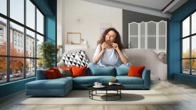 Young African-American woman eating chocolate at home Wall mural