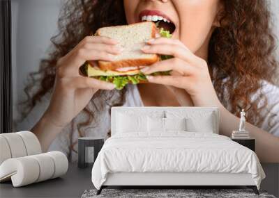 Young African-American woman eating tasty sandwich at home, closeup Wall mural