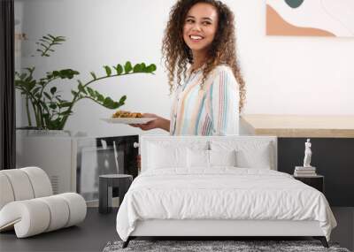 Young African-American woman putting plate with food into microwave oven in kitchen Wall mural