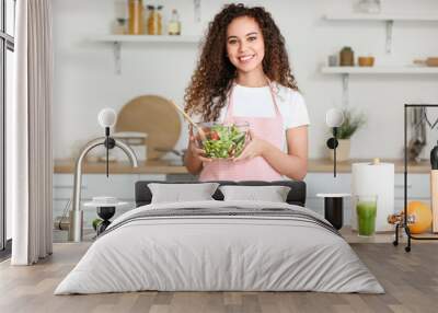 Young African-American woman with healthy salad in kitchen Wall mural