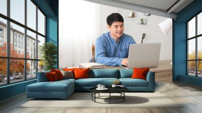 Young Asian man working on laptop at home Wall mural