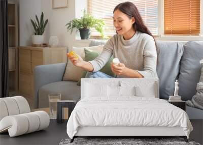 Young Asian woman choosing pills to take at home Wall mural