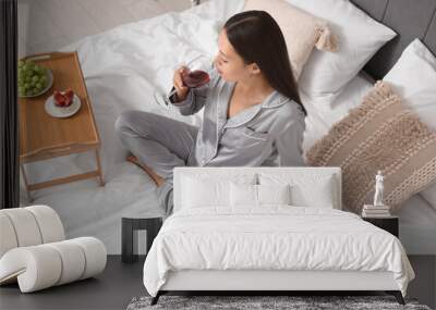 Young Asian woman drinking wine on bed in bedroom Wall mural