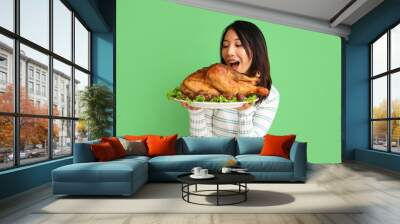 Young Asian woman with tasty turkey on color background. Thanksgiving Day celebration Wall mural