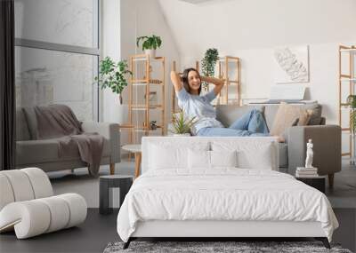 Young beautiful woman resting on cozy sofa in living room Wall mural