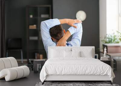 Young businessman stretching his spine while working in office Wall mural