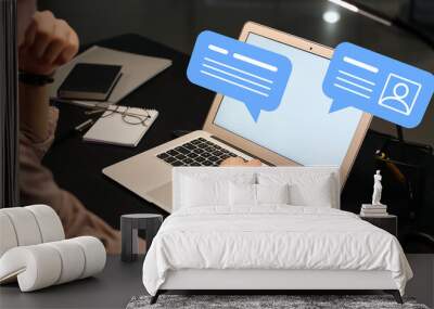 Young businessman with laptop chatting online in office Wall mural