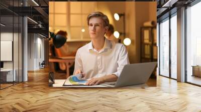 Young businessman working with documents in office at night Wall mural