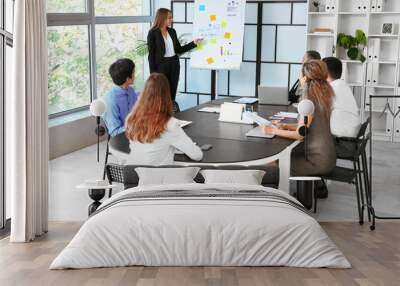 Young businesswoman giving presentation to her colleagues in office Wall mural