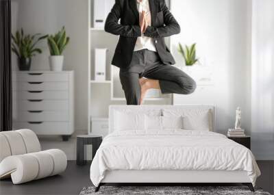 Young businesswoman practicing yoga in office Wall mural