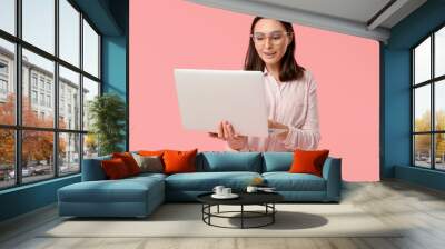 Young businesswoman with laptop on pink background Wall mural