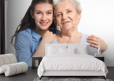 Young caregiver with senior woman on white background Wall mural