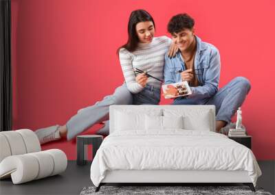 Young couple eating sushi on red background Wall mural