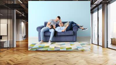 Young couple resting on sofa at home Wall mural