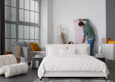 Young couple with Beagle dog wallpapering during repair in their new house Wall mural