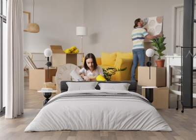 Young couple with cardboard boxes in their new house on moving day Wall mural