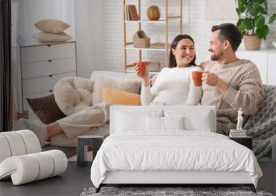 Young couple with cups of tea at home on autumn day Wall mural