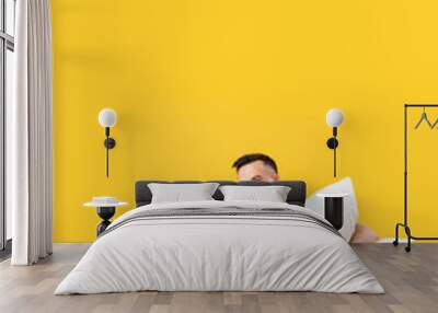 Young couple with pillows on yellow background Wall mural