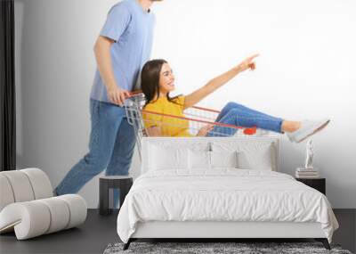 Young couple with shopping cart on white background Wall mural