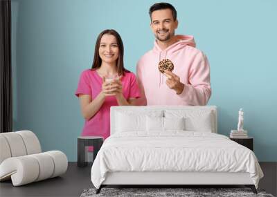 Young couple with tasty cookie and glass of milk on blue background Wall mural