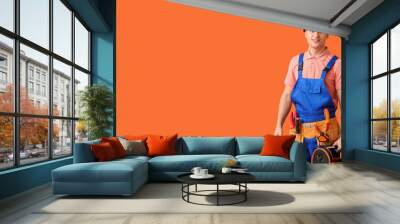 Young electrician with tools on orange background with space for text Wall mural