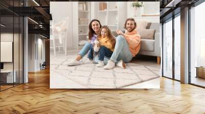 Young family sitting on soft carpet at home Wall mural