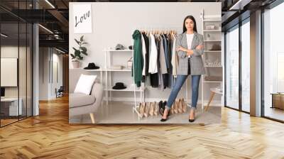 Young female clothes stylist at workplace Wall mural