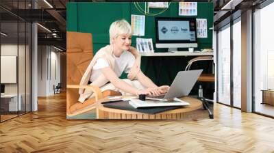 Young female graphic designer working with laptop on table in office Wall mural