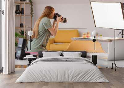 Young female photographer with professional camera taking picture of succulents in studio Wall mural