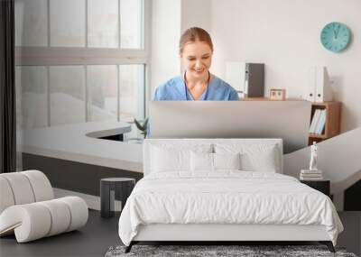 Young female receptionist working at desk in clinic Wall mural