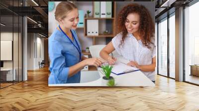 Young female receptionist working with patient in clinic Wall mural