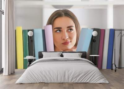 Young female student choosing books in library Wall mural