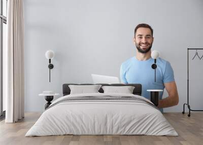 Young freelancer with laptop on light background Wall mural