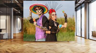 Young happy couple dressed for Mexico's Day of the Dead (El Dia de Muertos) with maracas in park outdoors Wall mural