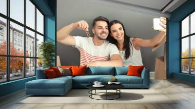 Young happy couple taking selfie with house key at new home Wall mural