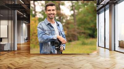 Young male photographer with camera outdoors Wall mural