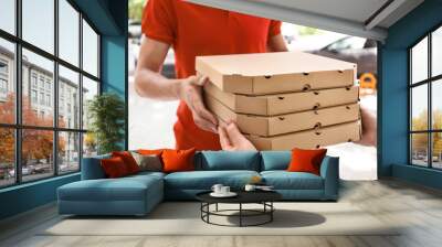 Young man giving pizza boxes to woman outdoors. Food delivery service Wall mural