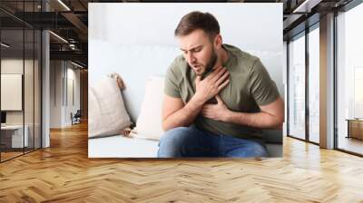 Young man having asthma attack at home Wall mural