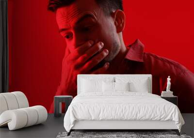 Young man having panic attack on red background, closeup Wall mural