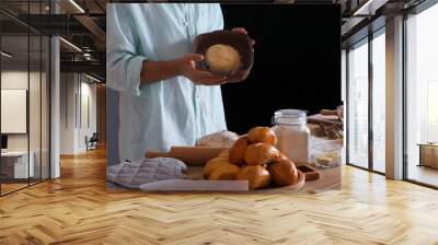 Young man holding baking dish with raw bread in bakery Wall mural