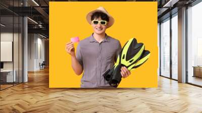 Young man in sunglasses with credit card and flippers on yellow background Wall mural