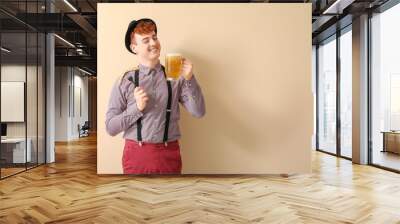 Young man in traditional German clothes with beer and sausage on beige background Wall mural