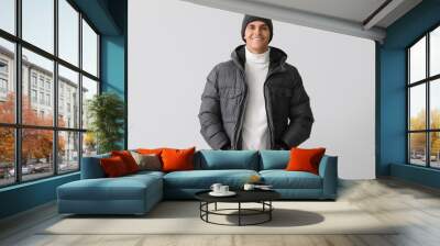 Young man in warm puffer jacket on light background Wall mural